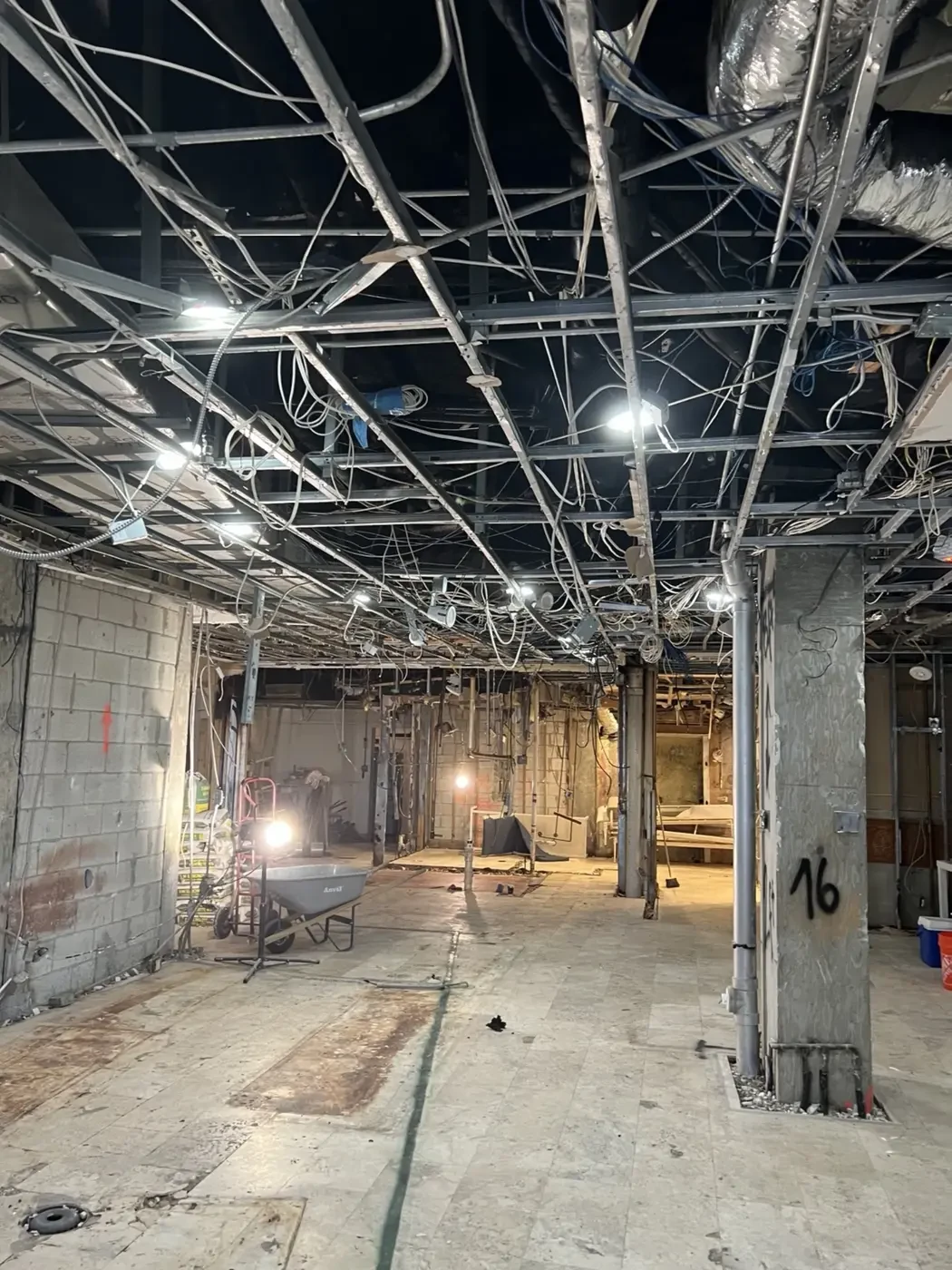 Before renovation photo of the Brisa Casa restaurant lounge space on Ocean Drive in South Beach, Miami, showing exposed ceiling grid, electrical wiring, and demolition conditions.