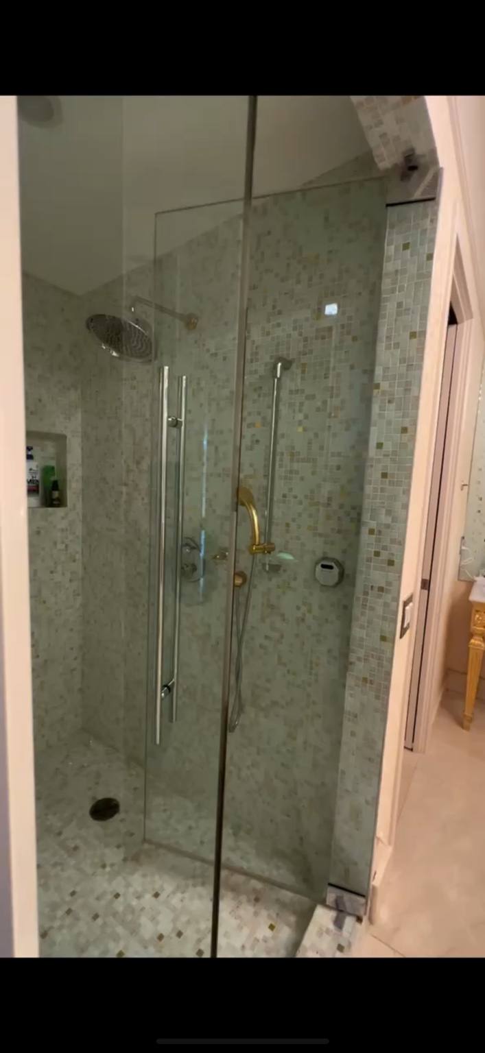 Before renovation: original primary bathroom shower door and finishes at Fisher Island residence prior to IV Atelier redesign