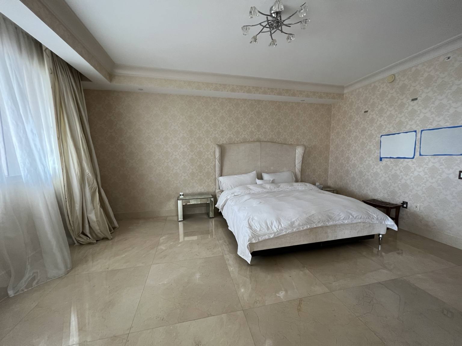 Before renovation: original primary bedroom with dated wallcovering and large-format marble floors at Fisher Island residence prior to IV Atelier redesign
