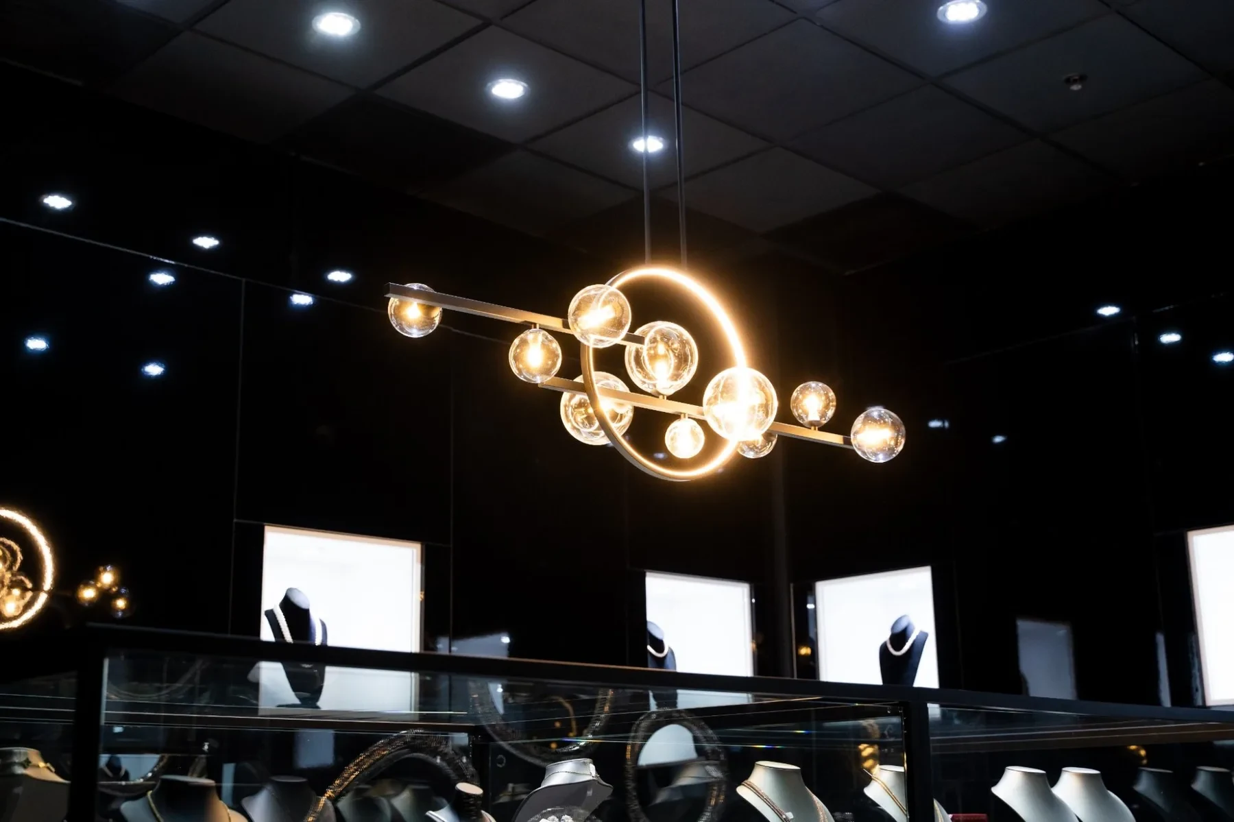 Luxzen sculptural chandelier — brass ring and glass globe pendants.