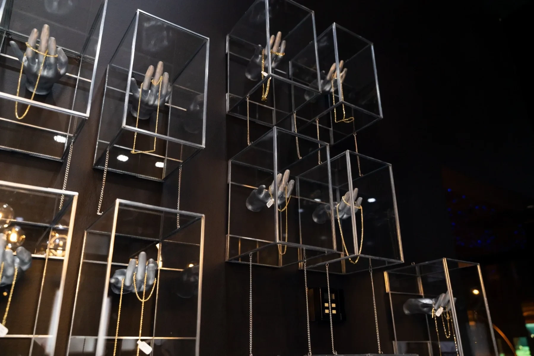 Luxzen display wall — suspended glass boxes with jewelry hand sculptures.