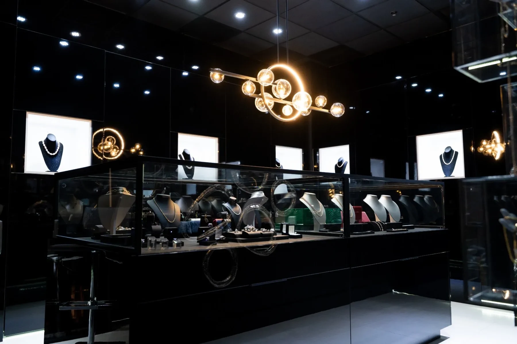 Luxzen jewelry display counter with sculptural chandelier overhead.
