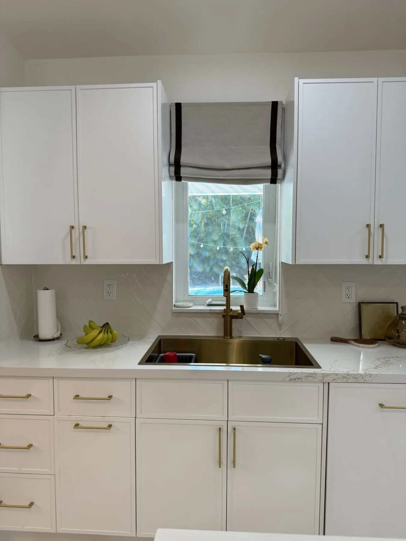San Souci Residence — kitchen sink with gold faucet and herringbone backsplash.