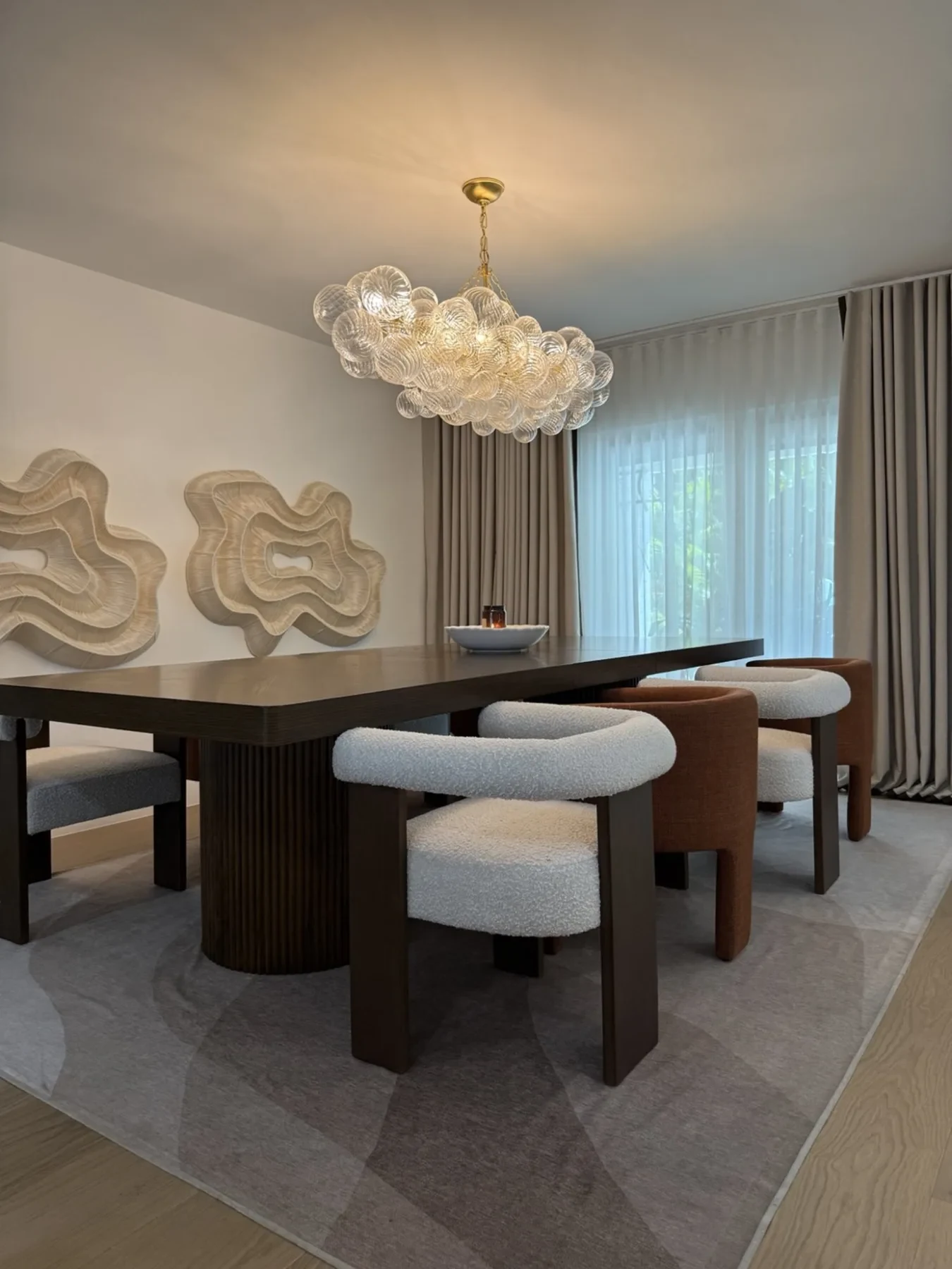 San Souci Residence — dining table with mixed boucle and rust chairs.