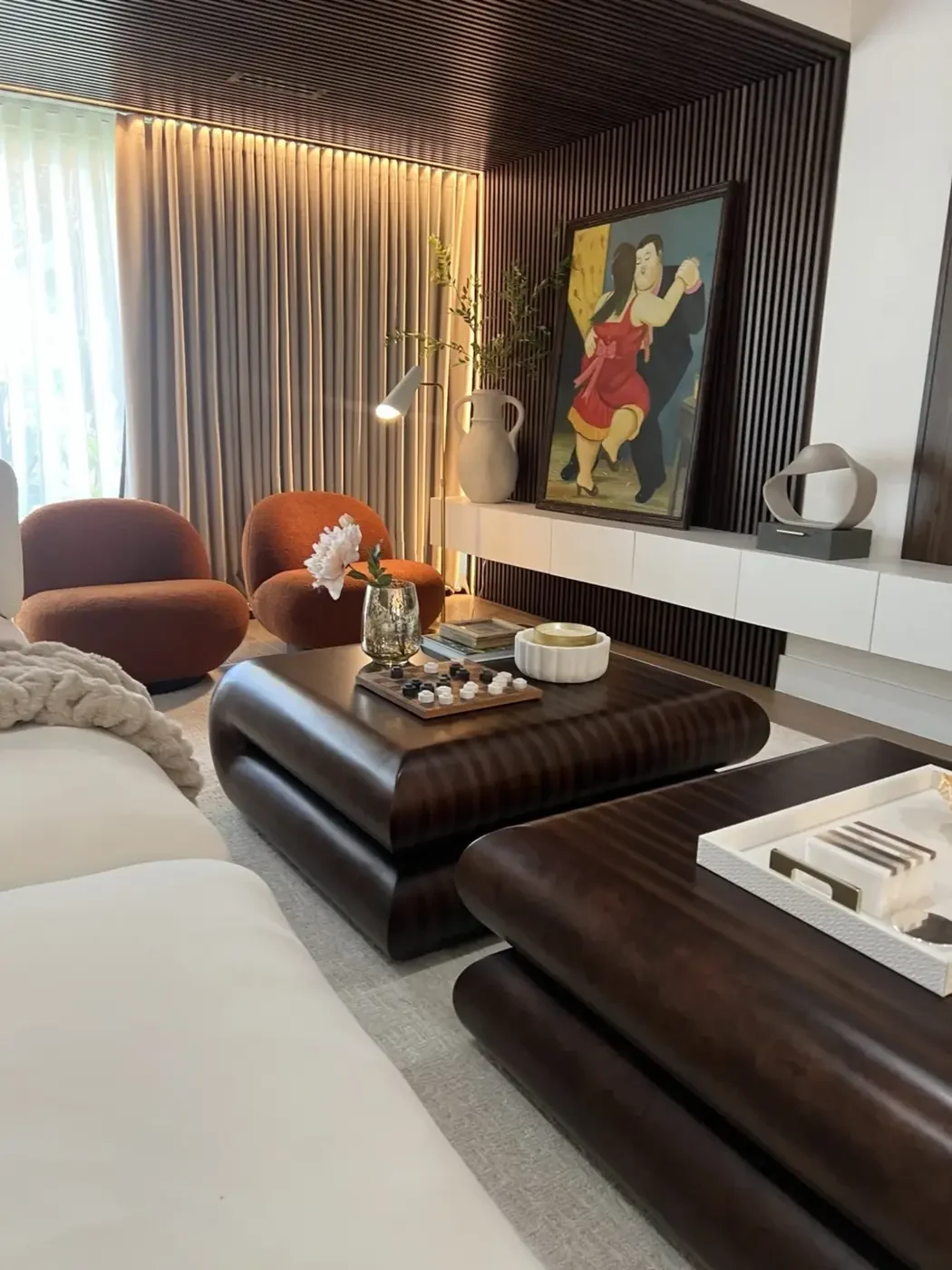 San Souci Residence — sculptural dark walnut coffee tables with Botero painting in background.