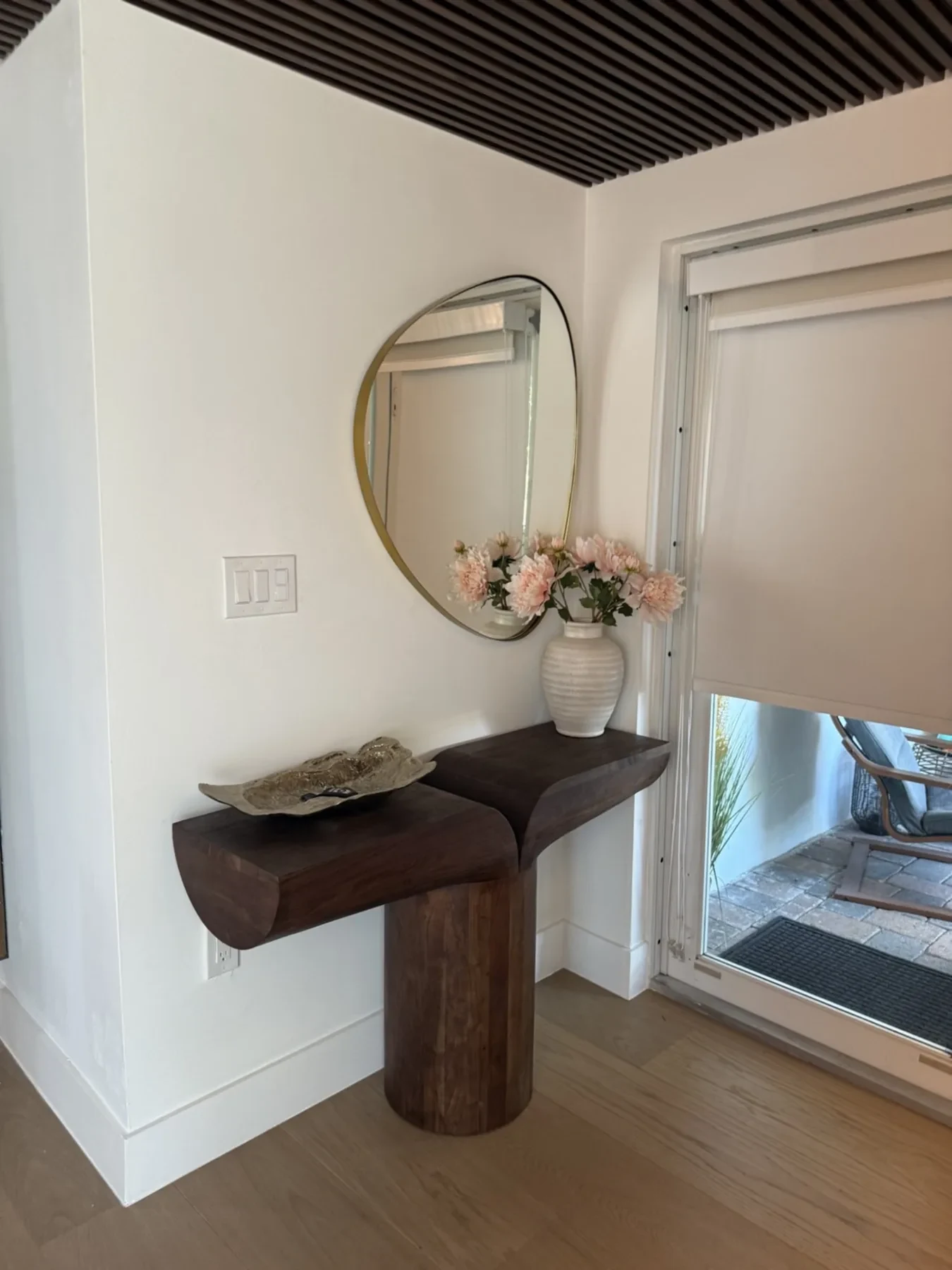 San Souci Residence — entry console with organic mirror and pink flower arrangement.