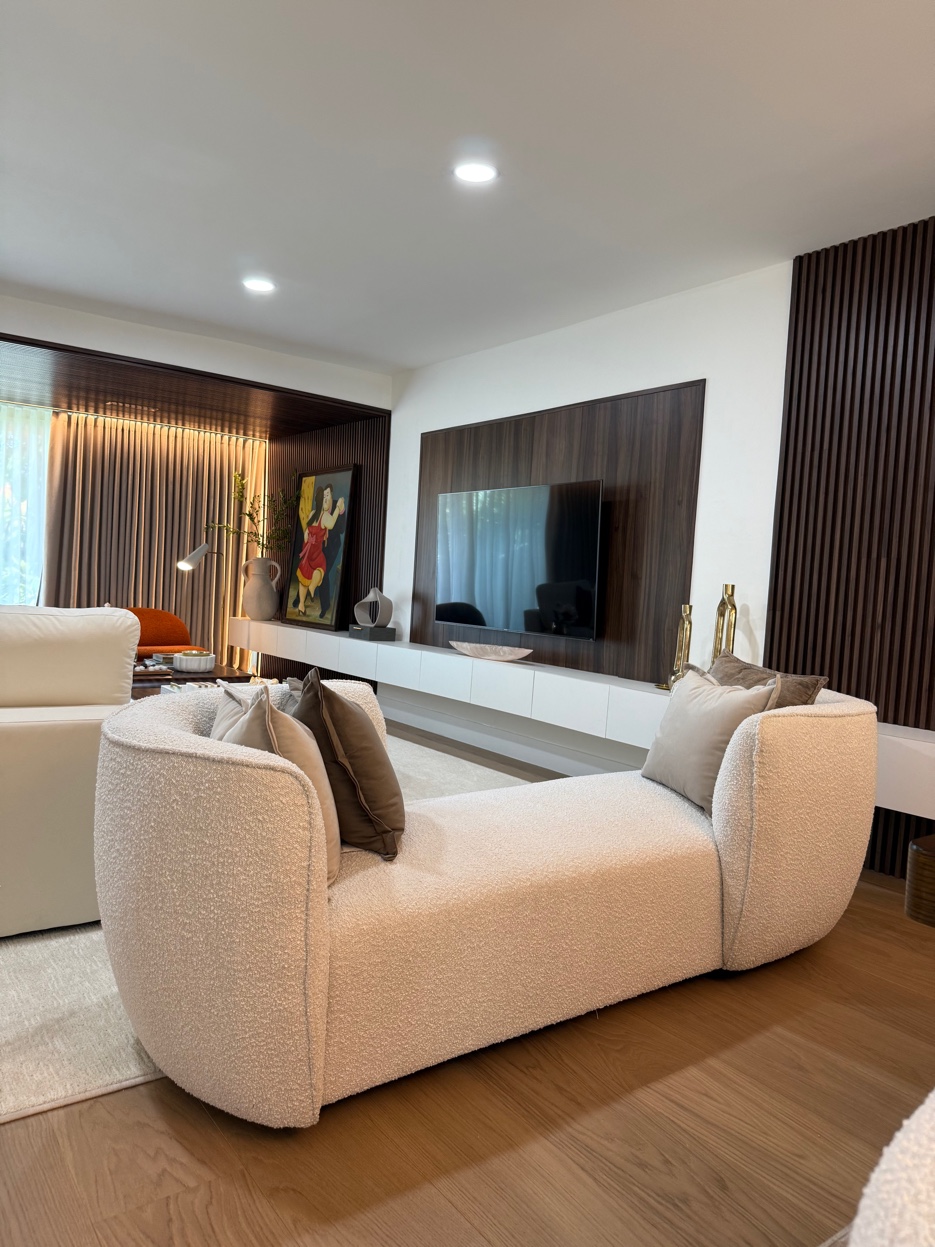 San Souci Residence — boucle sofa with TV wall and slatted wood panels to ceiling.